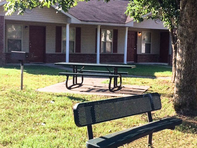 two picnic tables in a park in front of a building