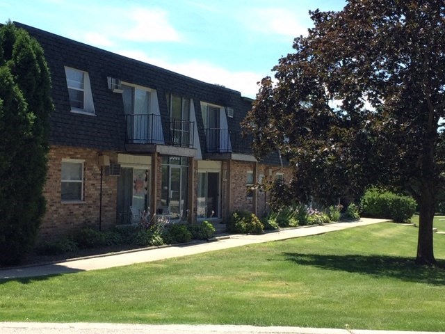 a brick apartment building with a lawn and trees