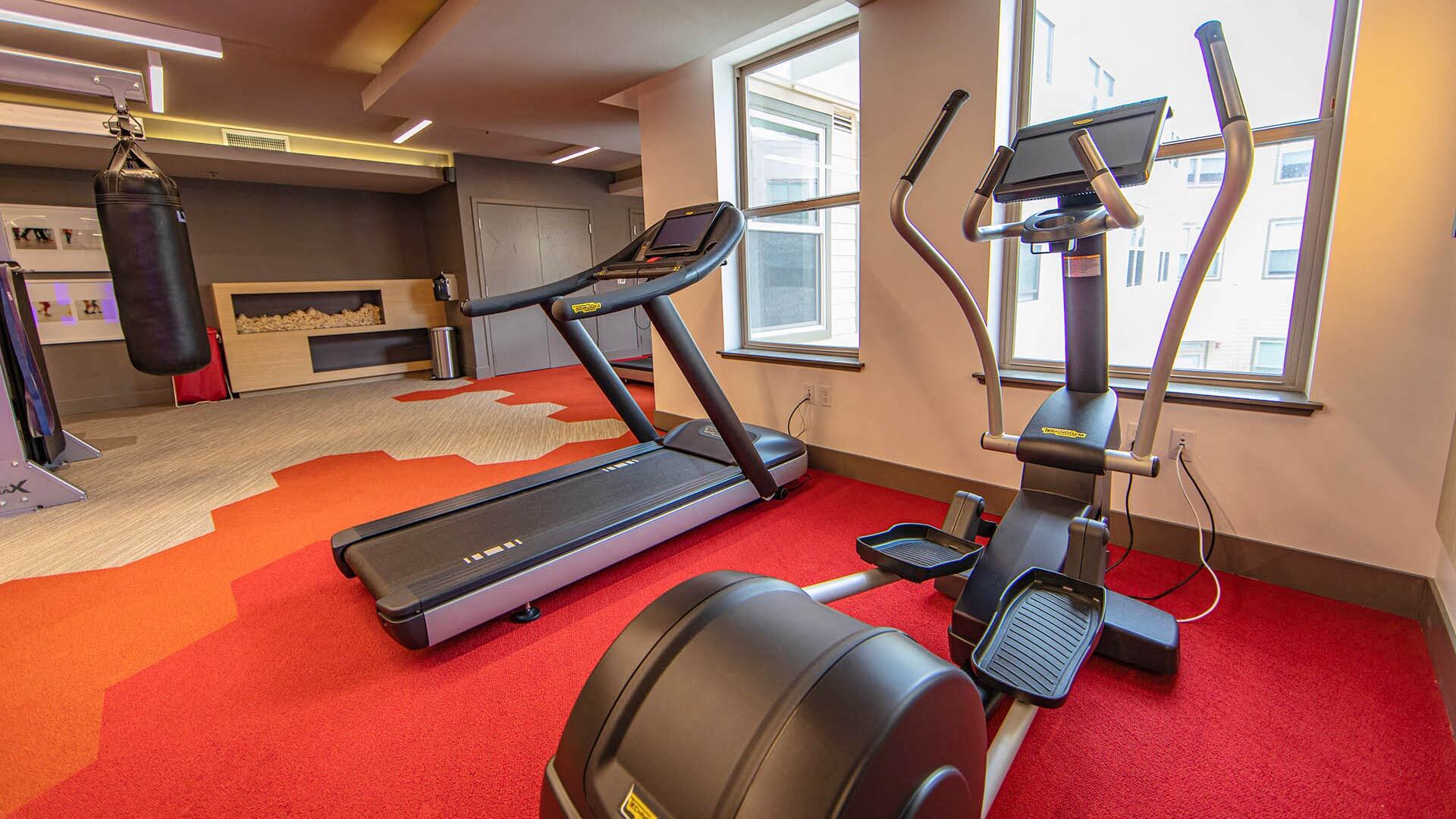 a gym with a treadmill and a punching bag on the floor
