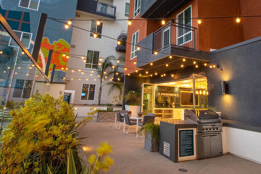 a patio with a grill and lights on a building