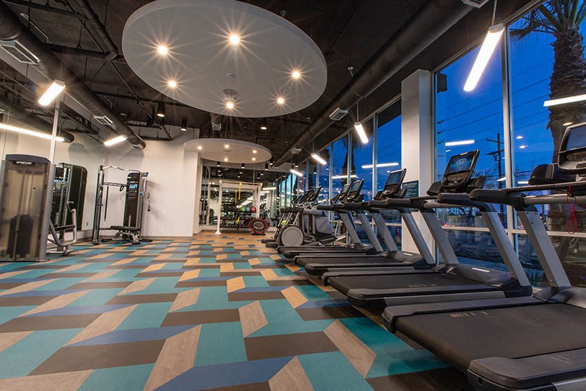 a gym with cardio machines and weights on a colorful floor
