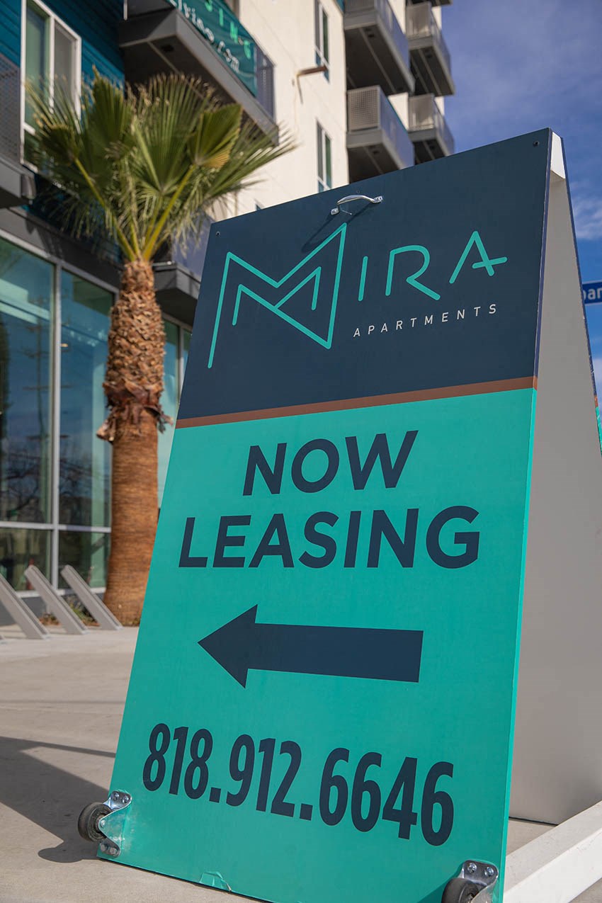 a now leasing sign in front of a building