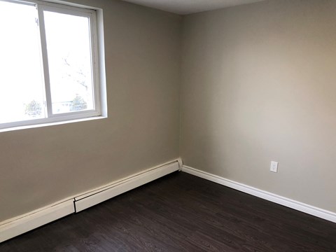an empty room with a window and wooden floors