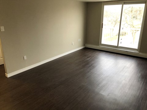 an empty living room with wood floors and a window