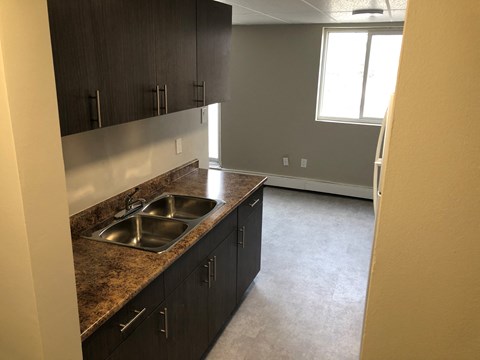 an empty kitchen with a sink and wooden cabinets