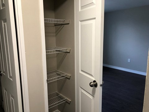 a walk in closet with empty shelves and a door