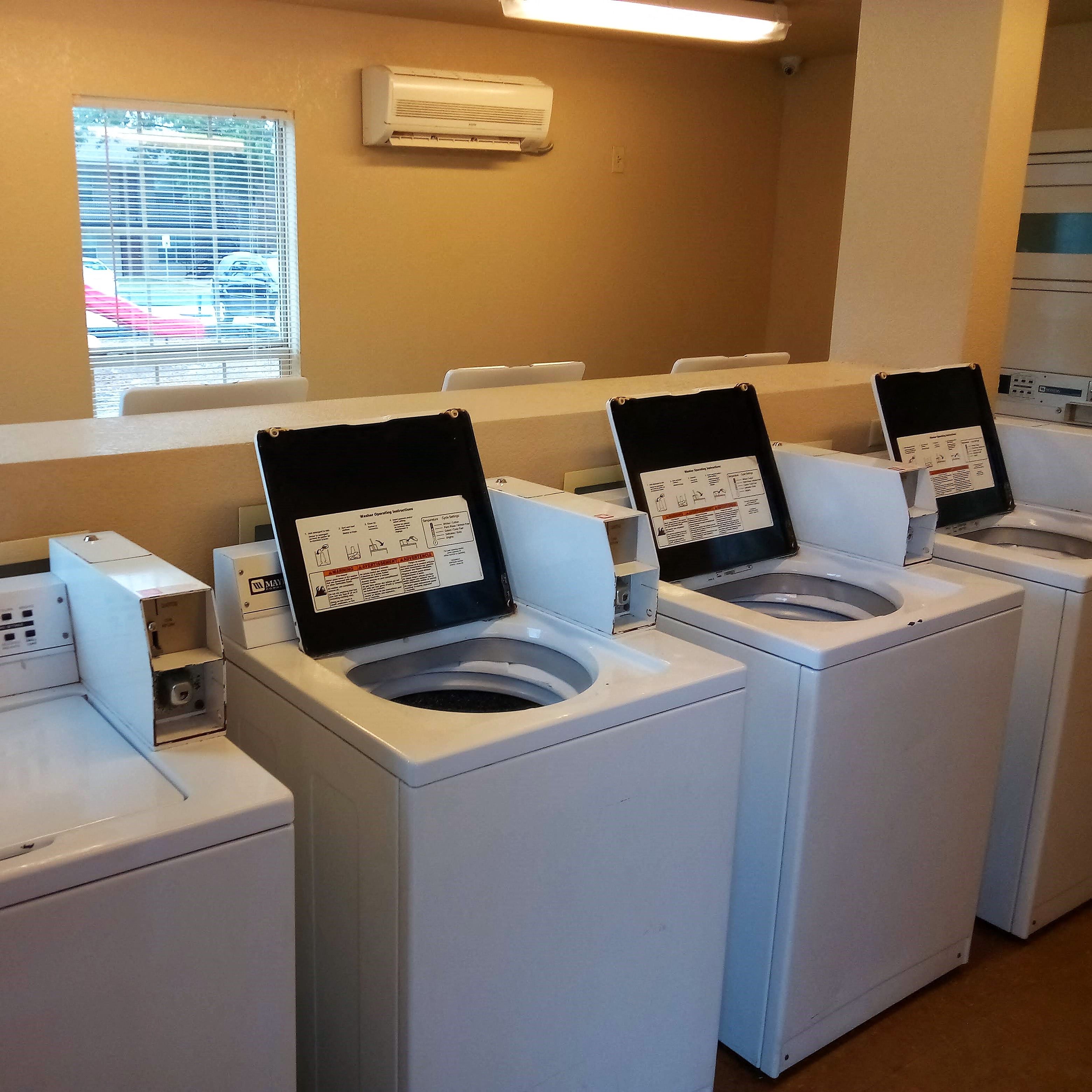 a row of washing machines with washing machines and dryers on them