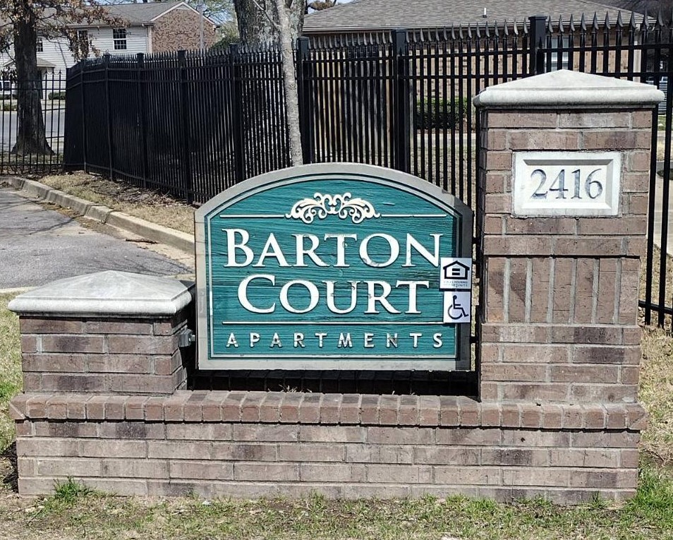 a sign for the baron court apartments in front of a fence