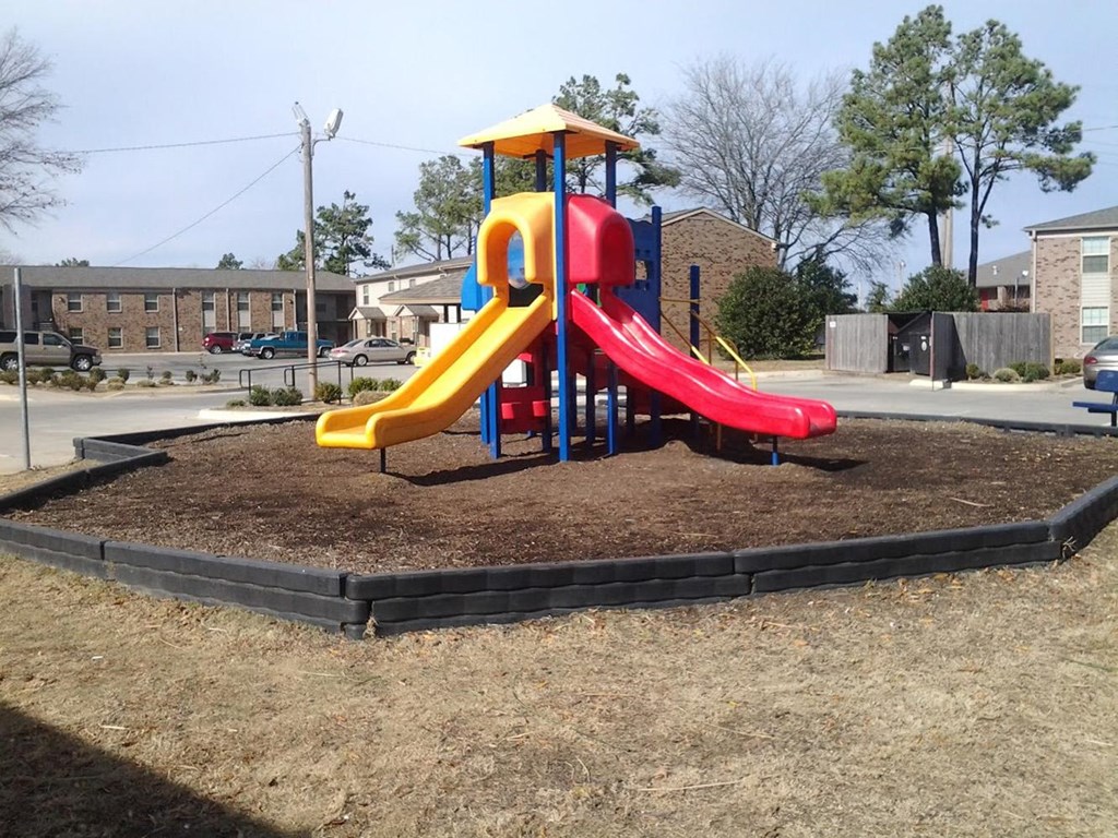 a playground with a colorful slide on a dirt