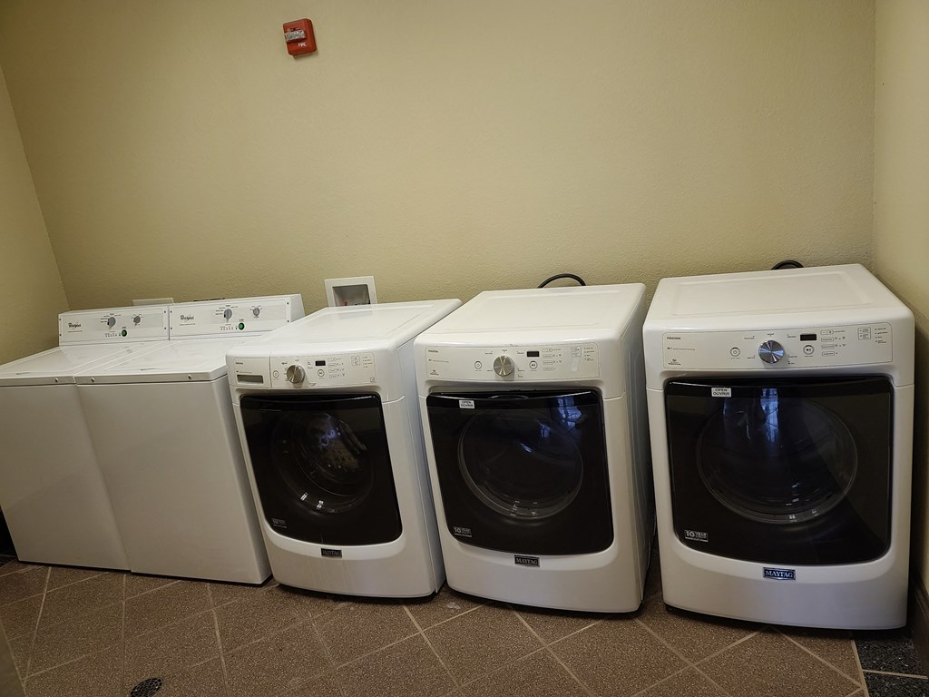 a row of four washers and dryers in a laundry room