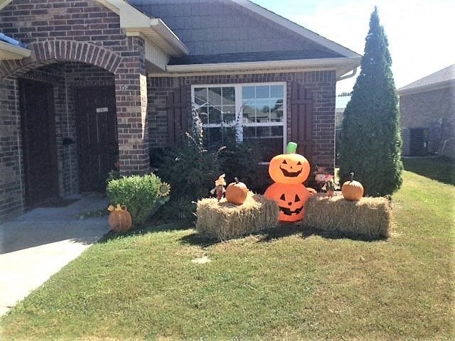 a house with pumpkins on hay bales in a yard