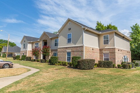 an apartment building with brick and white siding and green grass