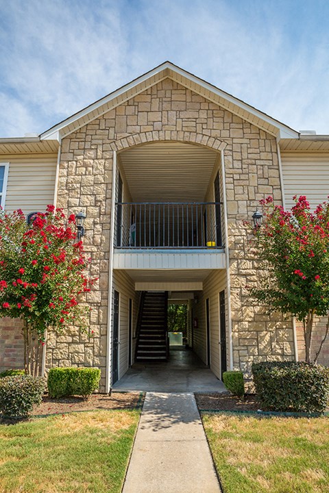 a stone building with a covered walkway leading to a balcony