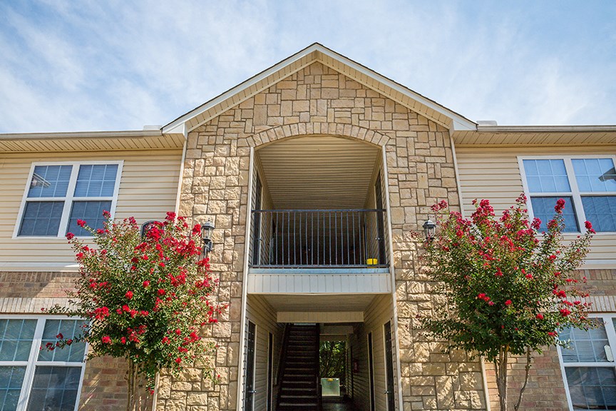 a brick house with a balcony and two red flowers