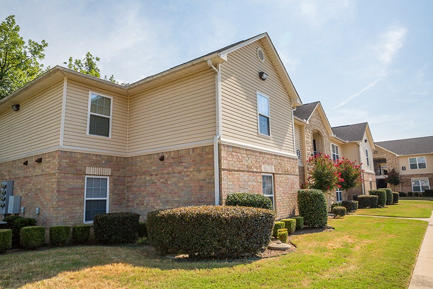 an apartment building with bushes and trees in front of it