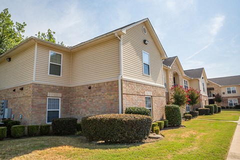 an apartment building with bushes and trees in front of it