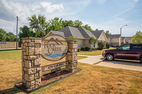 a car parked in front of a rock retaining wall with a sign