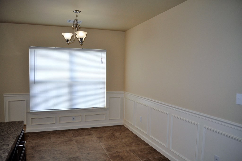 a dining room with white wainscoting and a window