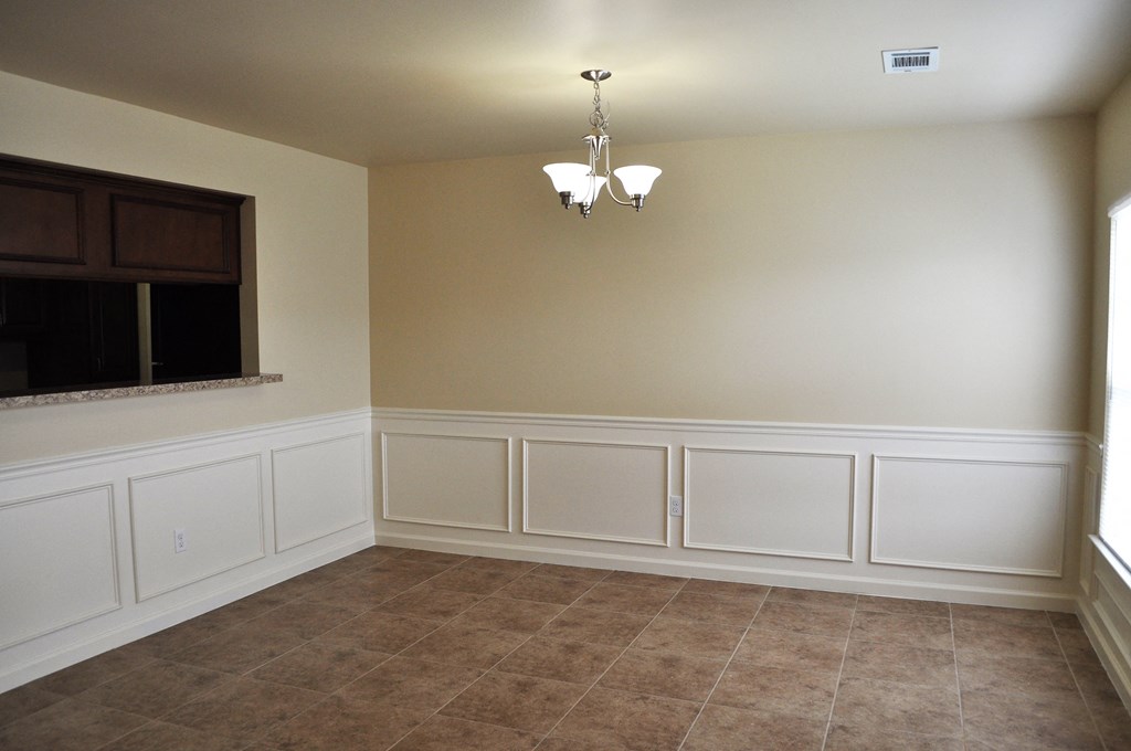 a dining room with white wainscoting and a window