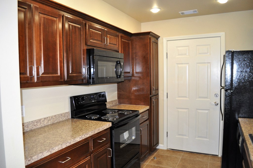 a kitchen with wood cabinets and black appliances and granite counter tops