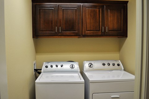 a laundry room with two washer and dryers and cabinets