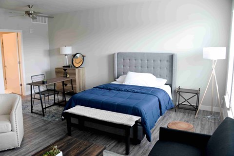 A bedroom with a bed, chair, and table.