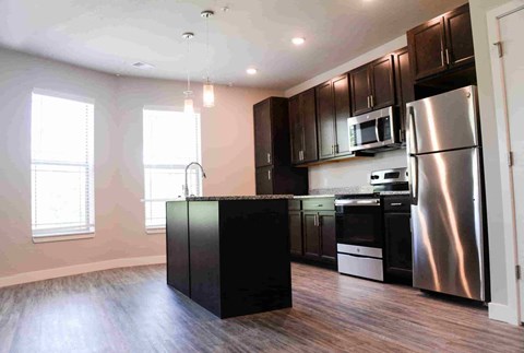 A kitchen with a black island and stainless steel appliances.