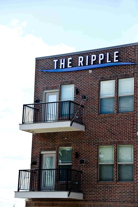 A brick building with a balcony and a sign that says "The Ripple".