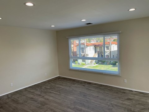 a living room with a large window and wooden floors