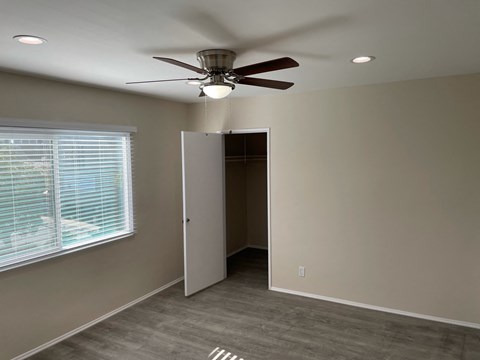 a bedroom with a ceiling fan and a door to a closet