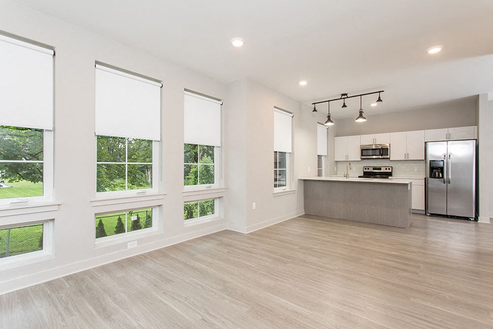 an open kitchen and living room with a stainless steel refrigerator
