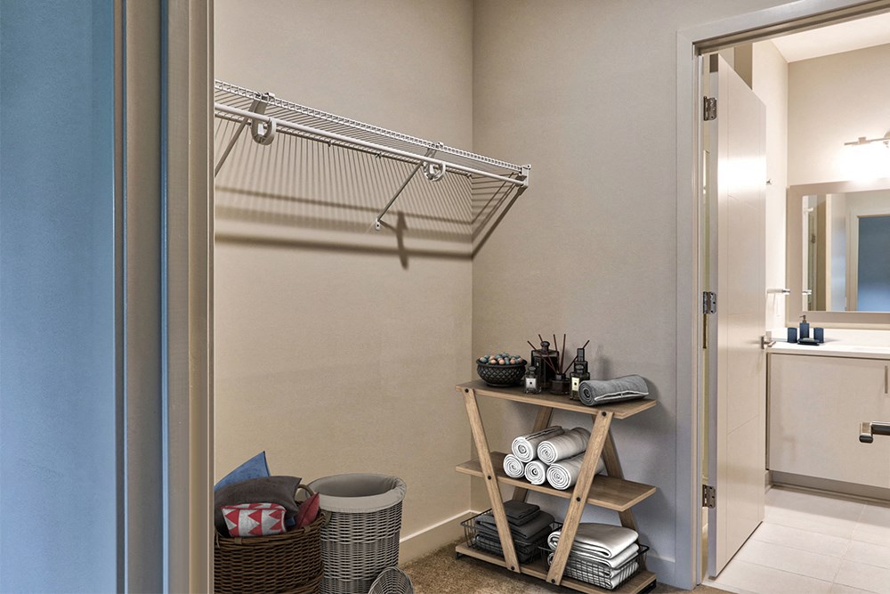 a closet with a shelving unit in a bathroom with a mirror