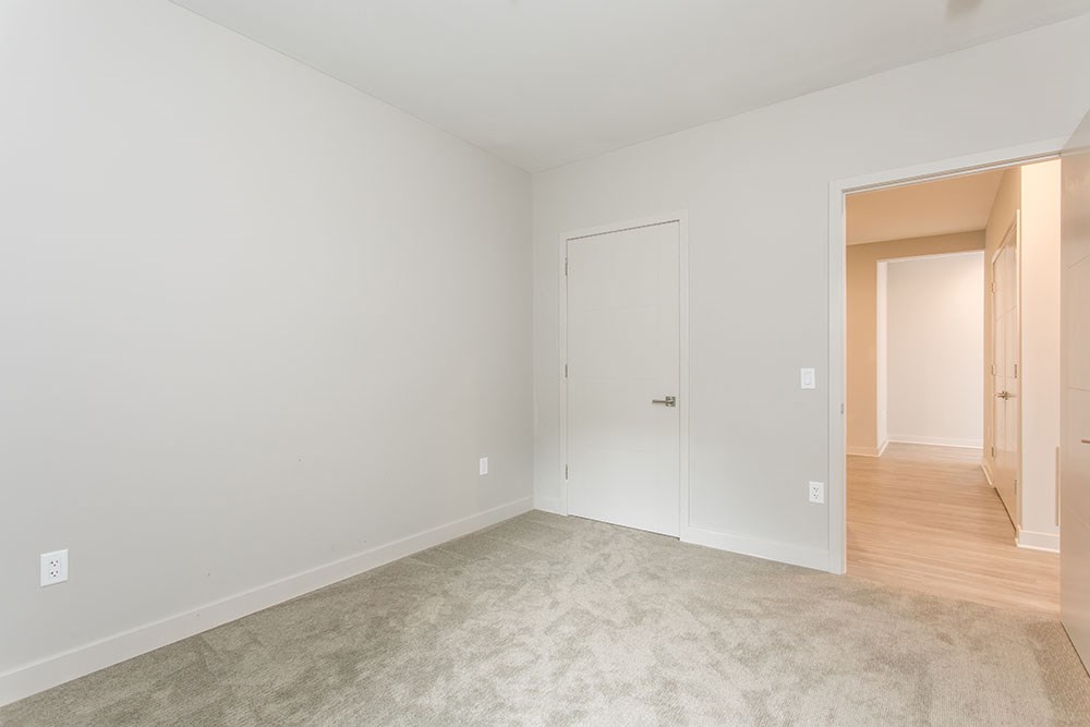 a bedroom with a door to a hallway and a carpeted floor
