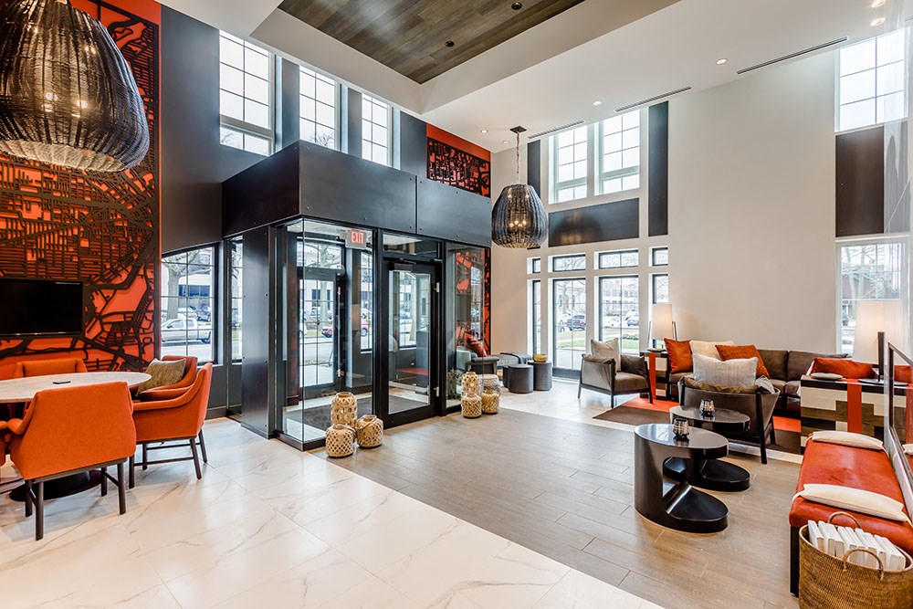 a lobby with chairs and tables and glass doors