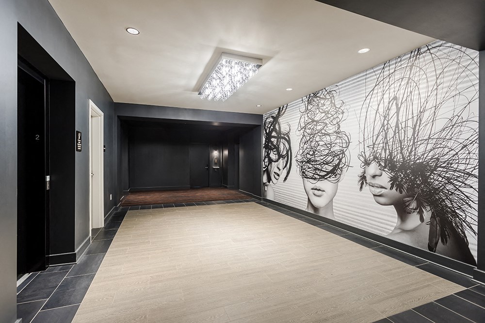 a hallway with a mural of two faces on the wall and a tiled floor