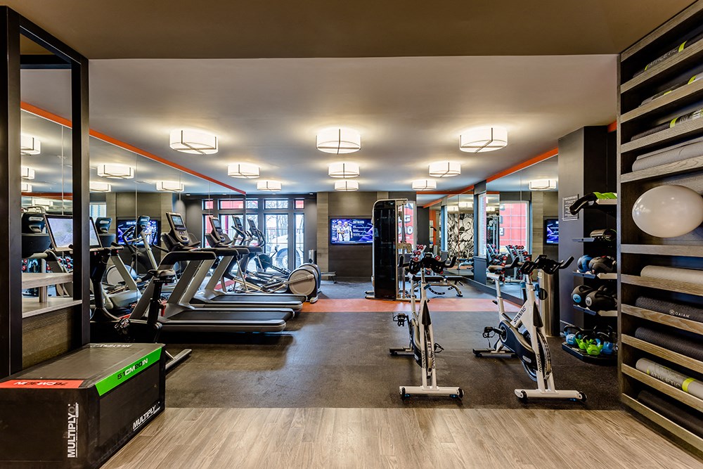 a gym with treadmills and other exercise equipment in a room with glass doors