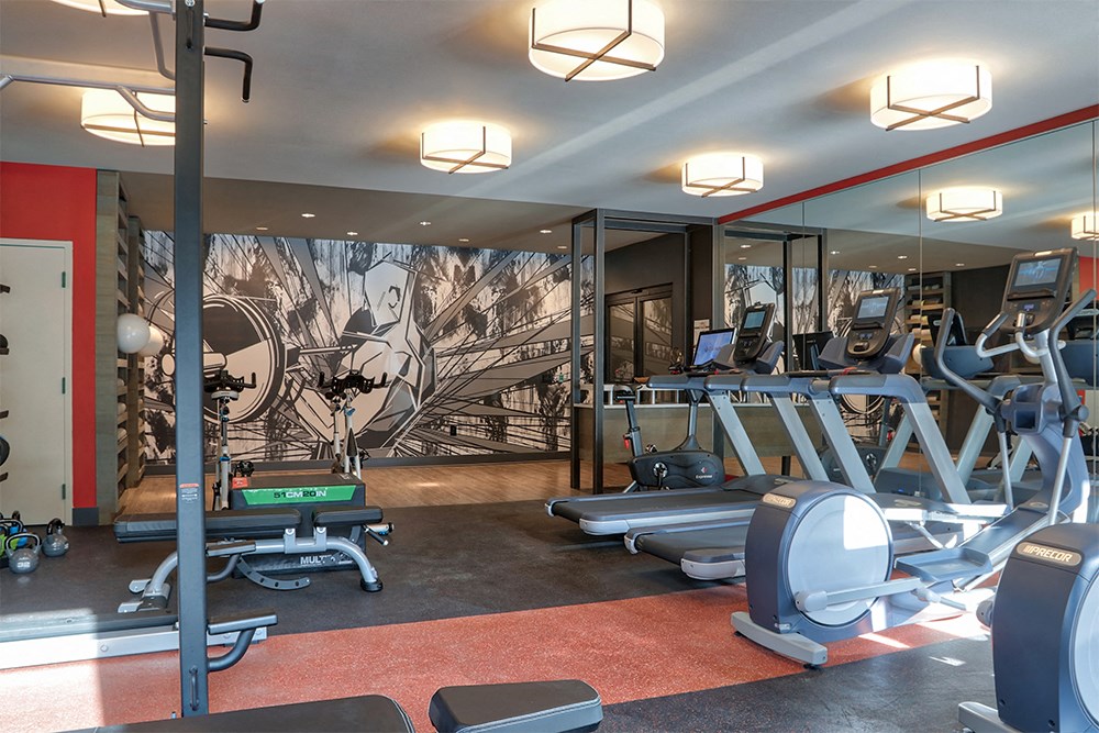 a gym with cardio equipment and a mural on the wall
