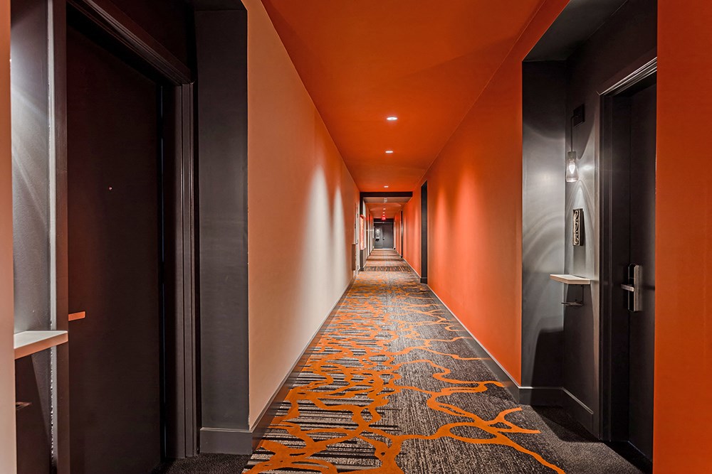 a long hallway with orange walls and a colorful carpet on the floor