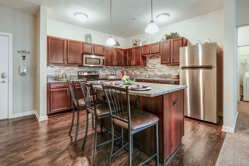 a kitchen with stainless steel appliances and a bar with chairs