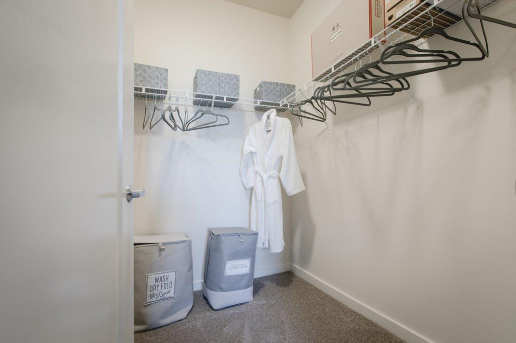 a closet with a rack and a laundry room with a trash can