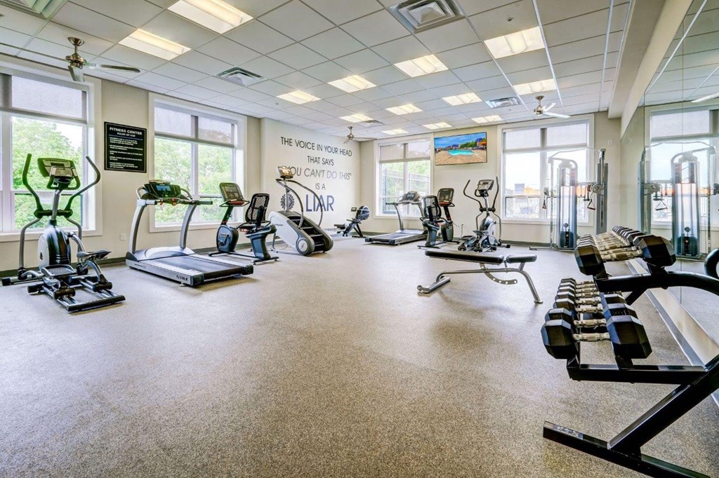 a gym with treadmills and other exercise equipment and windows