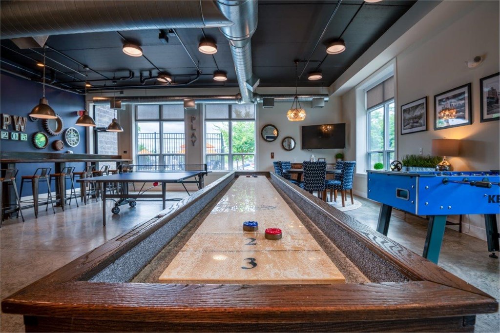 a shuffleboard table in a game room with a blue pool table