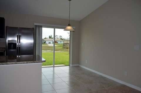 A kitchen with a refrigerator and a sliding glass door leading to a backyard.