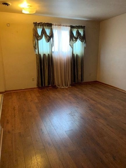 an empty living room with curtains and a wooden floor