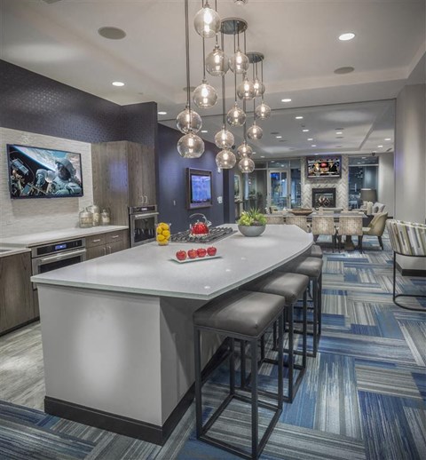 A modern kitchen with a bar area and a television mounted on the wall.