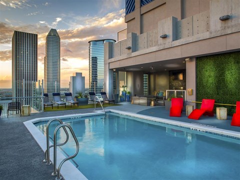 A swimming pool is surrounded by a red chair and a building with a green wall.