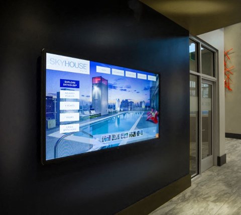 A large screen displays the name "SKYHOUSE" and images of a building and a pool.