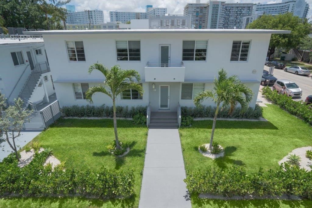 a white house with a lawn and palm trees in front