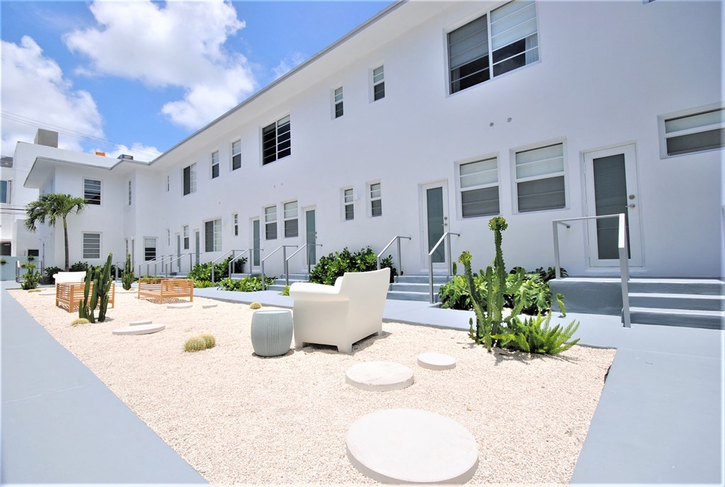 a large white building with a courtyard with chairs and tables