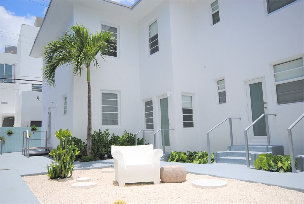 a white building with a palm tree and a white chair
